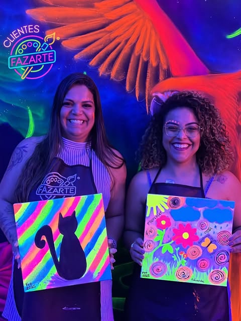 Duas visitantes sorrindo com pinturas neon coloridas